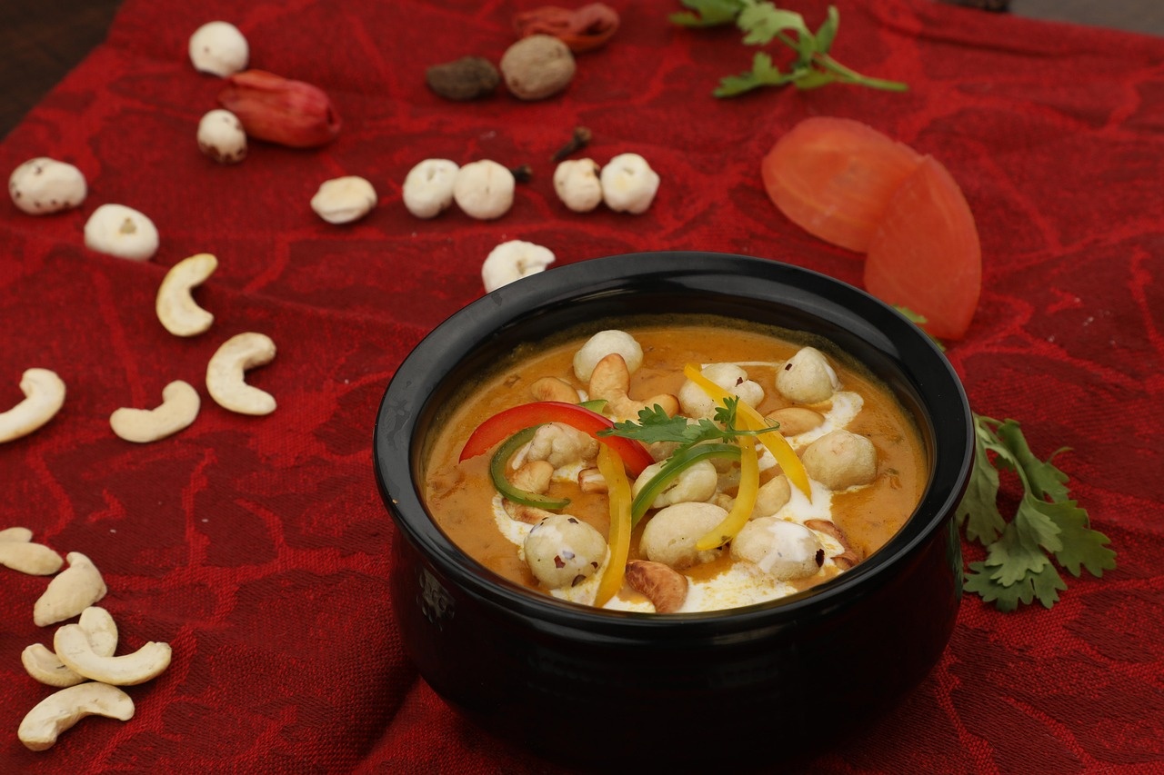 Cremiges Curry in schwarzer Schale mit Cashews und Paprika